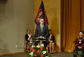 Na pierwszym planie prezydent Piotr Grzymowicz w czasie wystąpienia, w tle poczet sztandarowy UWM