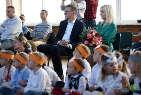 na pierwszym planie siedzą w kucki przedszkolaki w strojach lisków i zajączków, na drugim planie na krzesłach siedzą rodzice, prezydent Olsztyna i wicedyrektot ZSO 3 w Olsztynie
