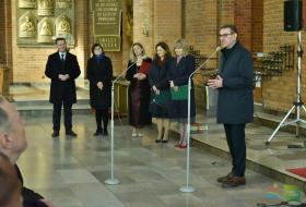 Po lewej stronie pięcioro członków kadry zarządzającej KZE podczas uroczystości w kościele, po prawej, prezydent Olsztyna Piotr Grzymowicz stoi przy mikrofonie