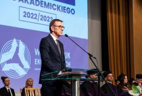 Piotr Grzymowicz stoi przy mikrofonie podczas inauguracji roku akademickiego na wydz. nauk ekonomicznych