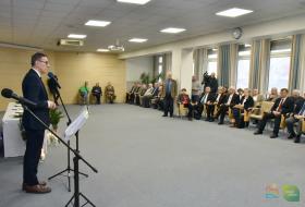Zdjęcie przedstawia stojacego przy mikrofonie i przemawiającego prezydenta Olsztyna na przeciw siądzący na kszesłach goście spotkania