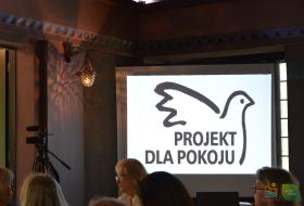 Zdjęcie przedstawia obraz wyświetlany na projektorze obraz z logo "Projekt dla Pokoju".