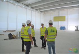 Zdjęcie przedstawia prezydenta Piotra Grzymowicza rozmawiającego z czwórką mężczyzn na terenie budowy.